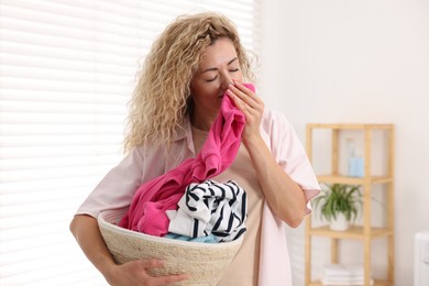 Photo of Woman with basket full of laundry indoors