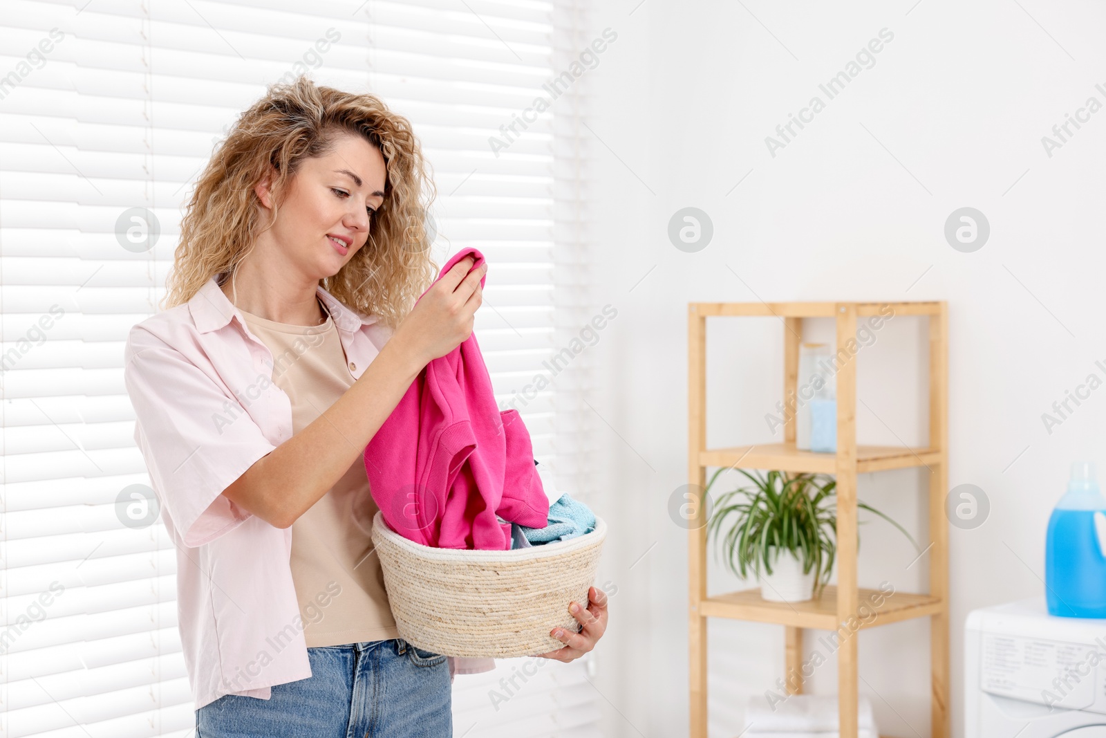 Woman with basket full of laundry indoors, space for text Photo of Woman with basket full of laundry indoors, space for text