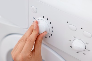 Photo of Woman using washing machine indoors, closeup. Laundry day