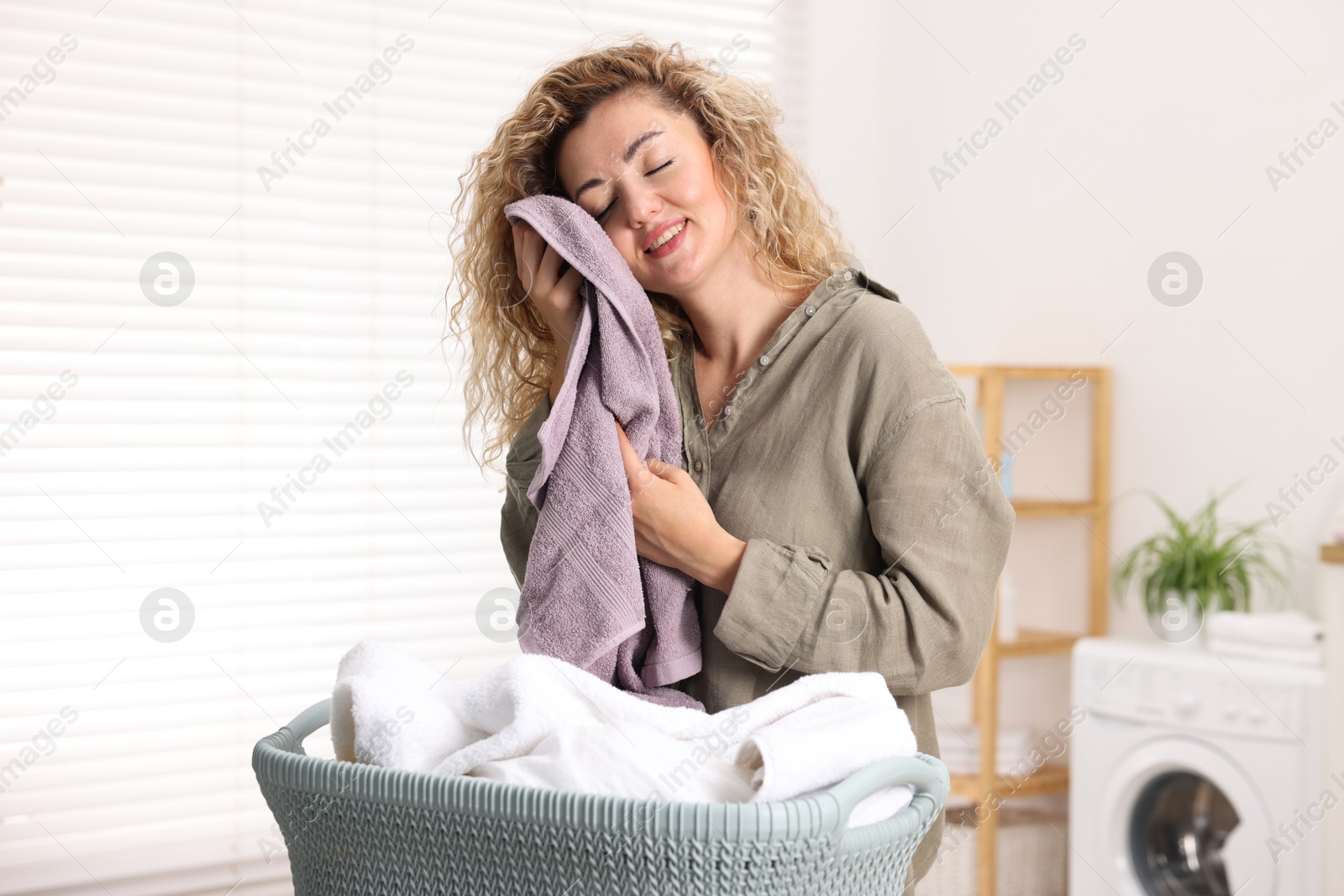 Happy woman with clean laundry at home Photo of Happy woman with clean laundry at home