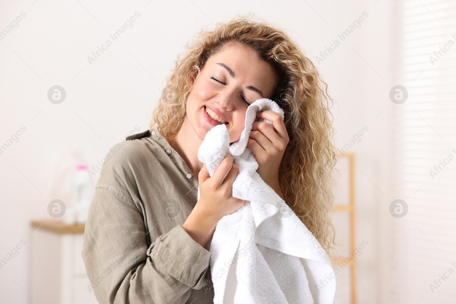 Photo of Happy woman with clean laundry at home