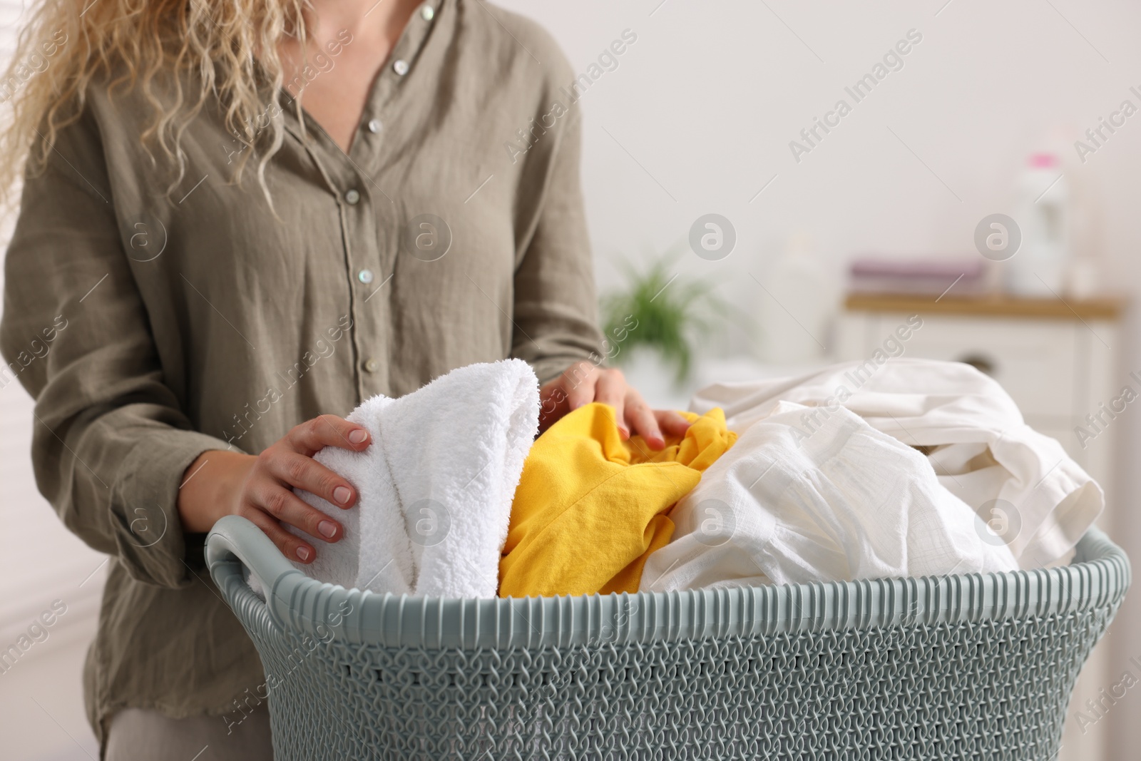 Photo of Woman with basket full of laundry indoors, closeup