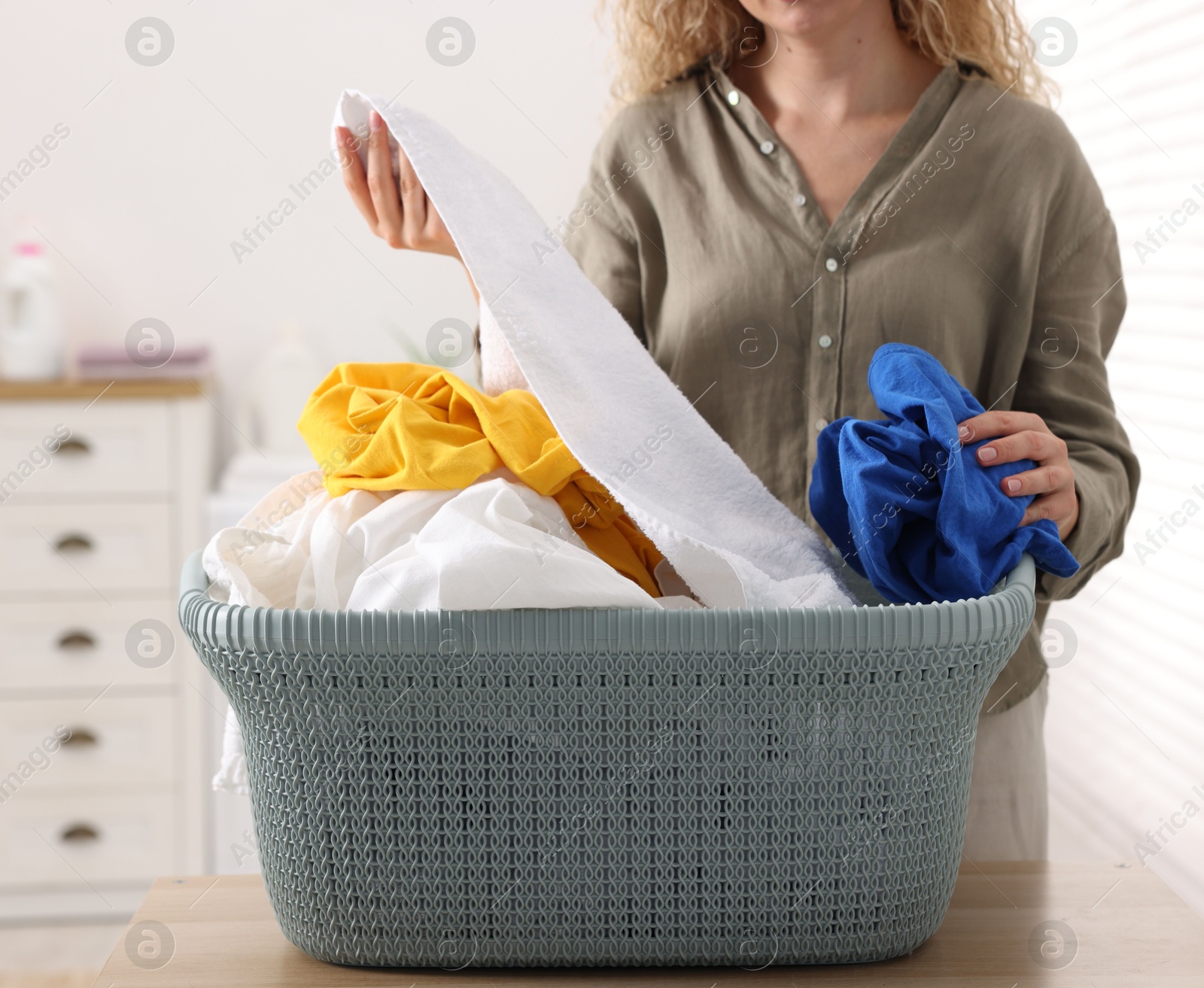 Photo of Woman with basket full of laundry indoors, closeup