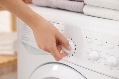 Photo of Woman using washing machine indoors, closeup. Laundry day