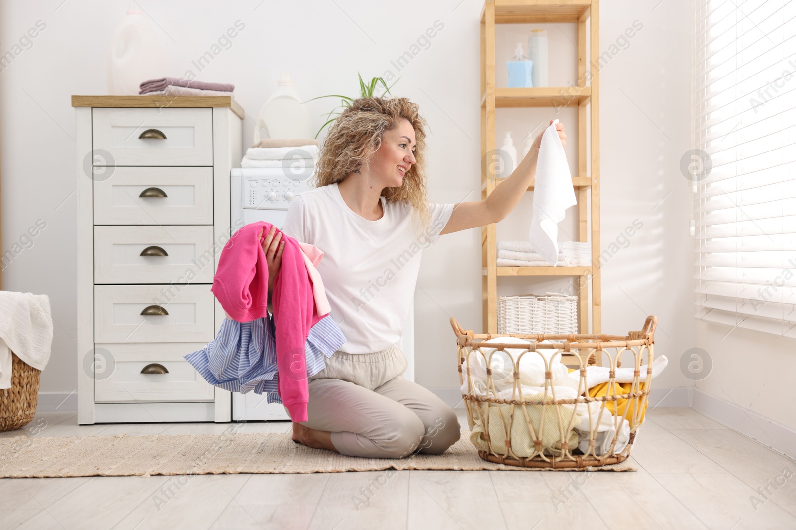 Photo of Woman with laundry near washing machine indoors