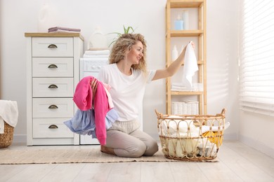 Photo of Woman with laundry near washing machine indoors