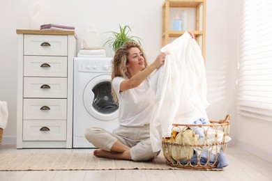 Photo of Woman with laundry near washing machine indoors
