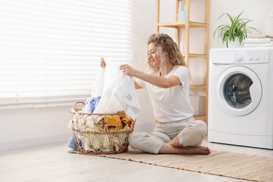 Photo of Woman with laundry near washing machine indoors