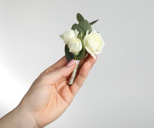 Photo of Woman with stylish small boutonniere on light grey background, closeup