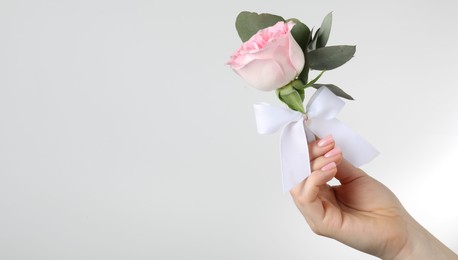Photo of Woman with stylish small boutonniere on light grey background, closeup. Space for text