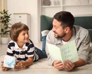 Photo of Happy Father's Day. Son giving his dad gift and card at home