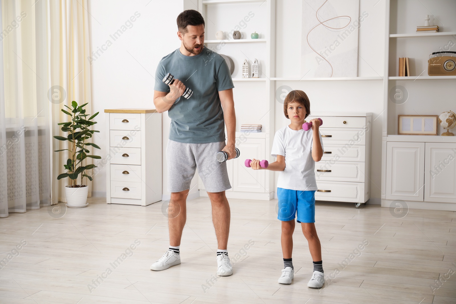 Father and son training with dumbbells at home Photo of Father and son training with dumbbells at home