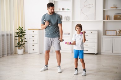 Photo of Father and son training with dumbbells at home