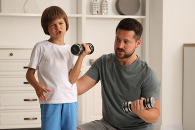 Photo of Father and son training with dumbbells at home