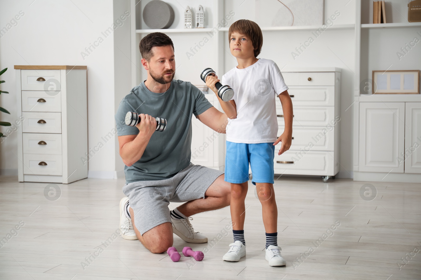Father and son training with dumbbells at home Photo of Father and son training with dumbbells at home