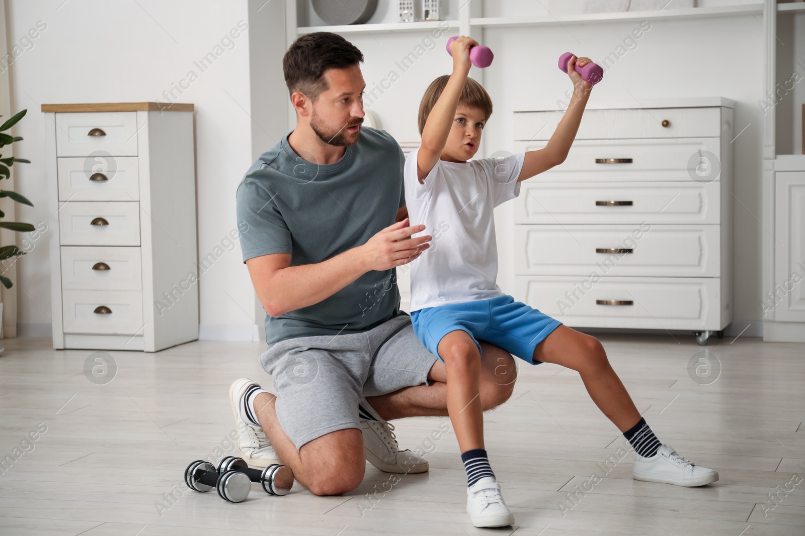 Father and son training with dumbbells at home Photo of Father and son training with dumbbells at home