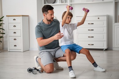 Photo of Father and son training with dumbbells at home