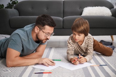 Photo of Father and son drawing together on floor at home