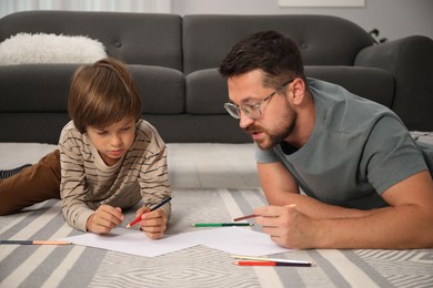 Photo of Father and son drawing together on floor at home