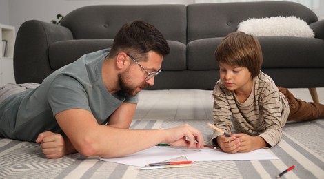 Photo of Father and son drawing together on floor at home