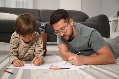 Photo of Father and son drawing together on floor at home