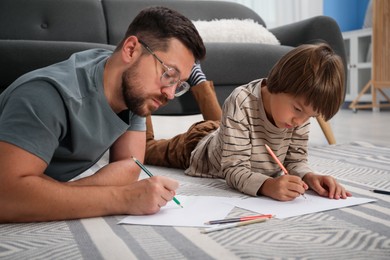 Photo of Father and son drawing together on floor at home