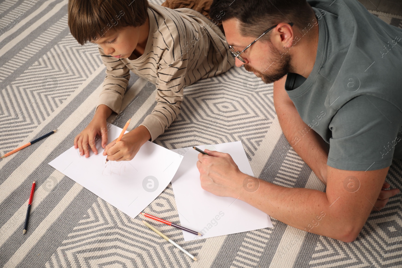 Father and son drawing together on floor at home Photo of Father and son drawing together on floor at home