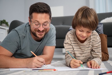 Photo of Father and son drawing together on floor at home