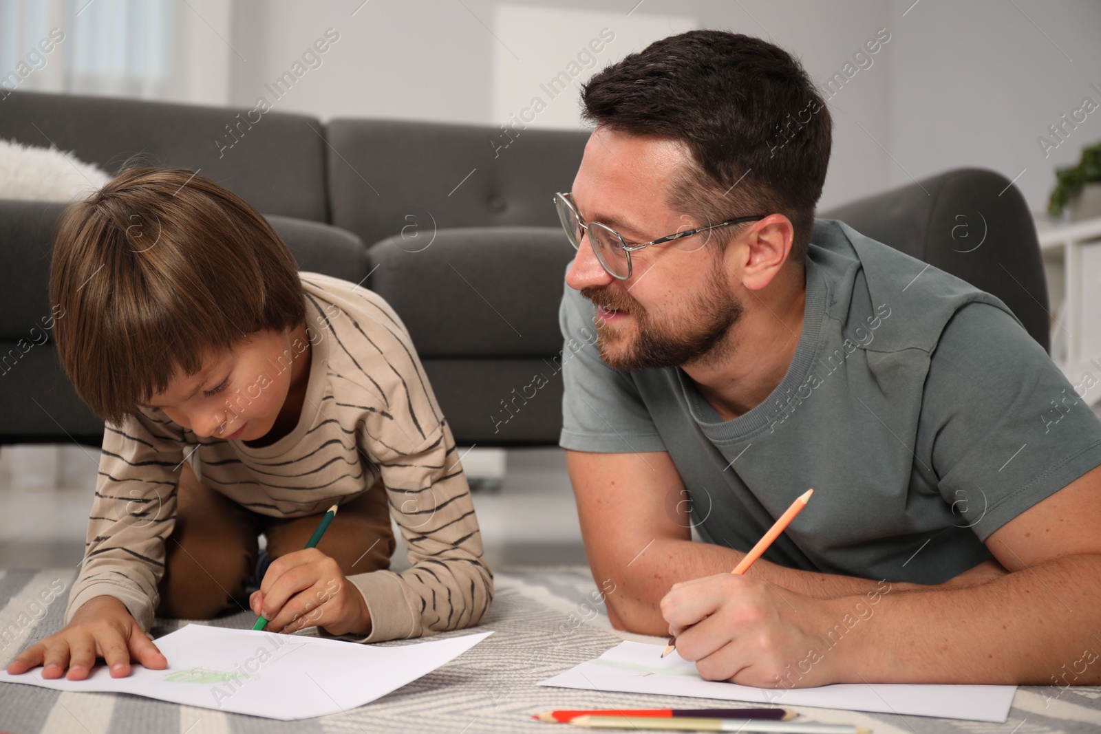 Photo of Father and son drawing together on floor at home