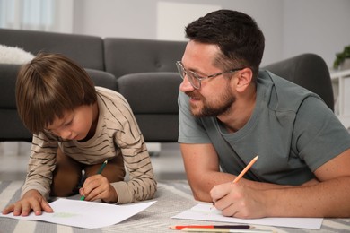 Photo of Father and son drawing together on floor at home