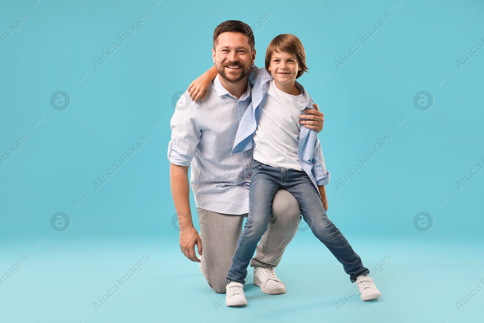 Father and son on light blue background Photo of Father and son on light blue background