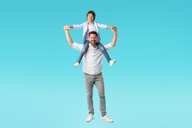 Photo of Father carrying his son on shoulders against light blue background