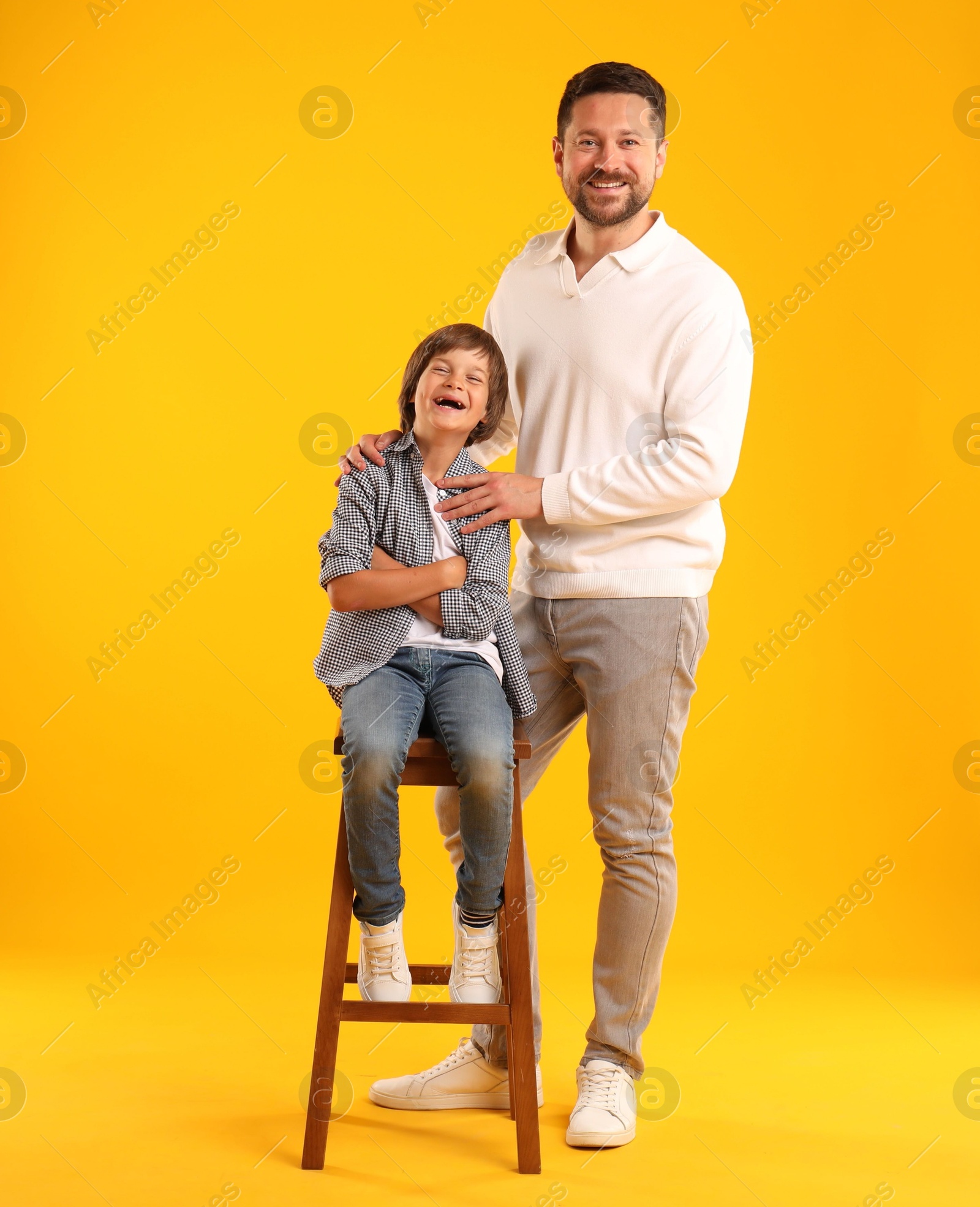 Father and son posing on yellow background Photo of Father and son posing on yellow background