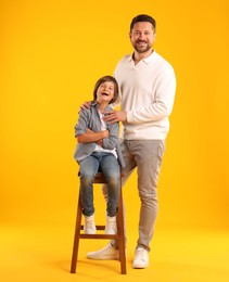 Photo of Father and son posing on yellow background