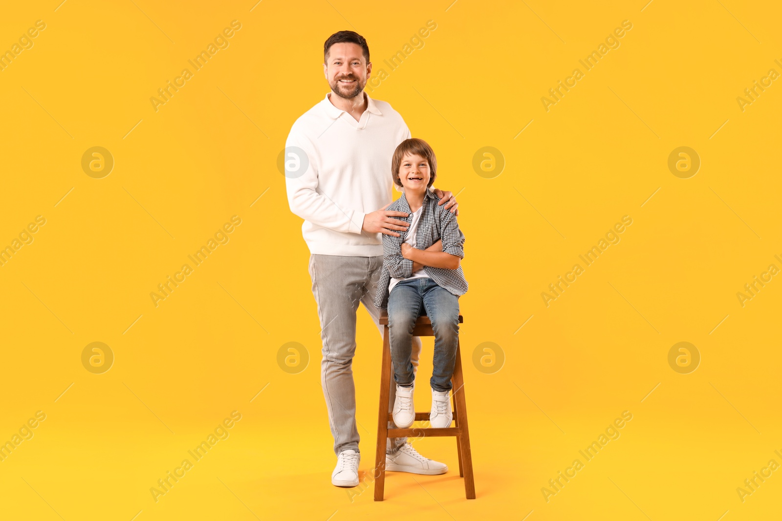 Father and son posing on yellow background Photo of Father and son posing on yellow background