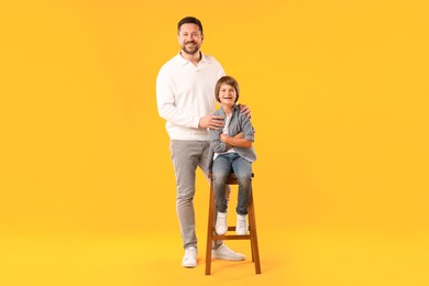 Photo of Father and son posing on yellow background