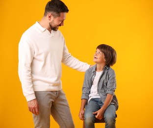 Photo of Father and son posing on yellow background