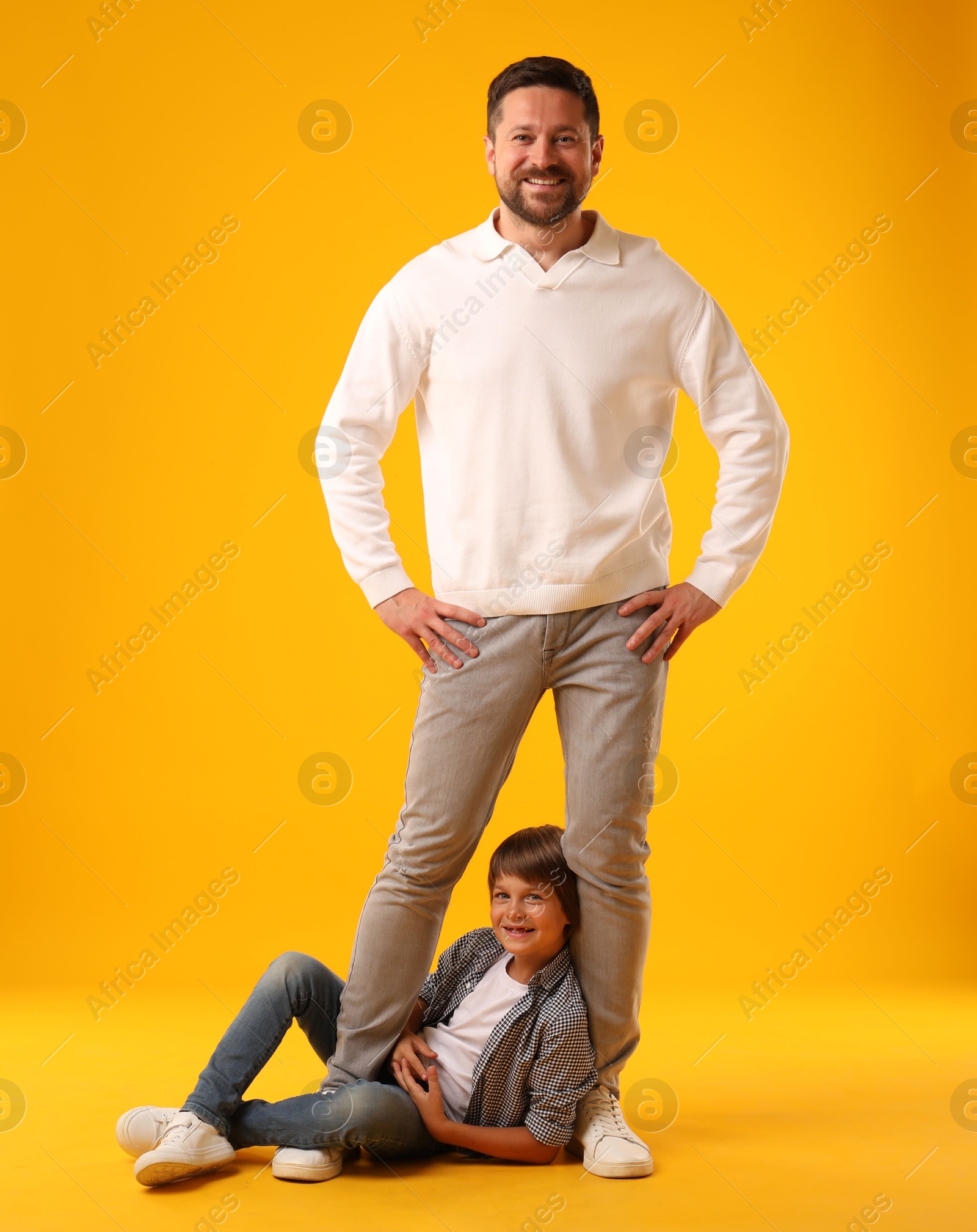 Father and son posing on yellow background Photo of Father and son posing on yellow background