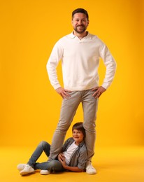 Photo of Father and son posing on yellow background