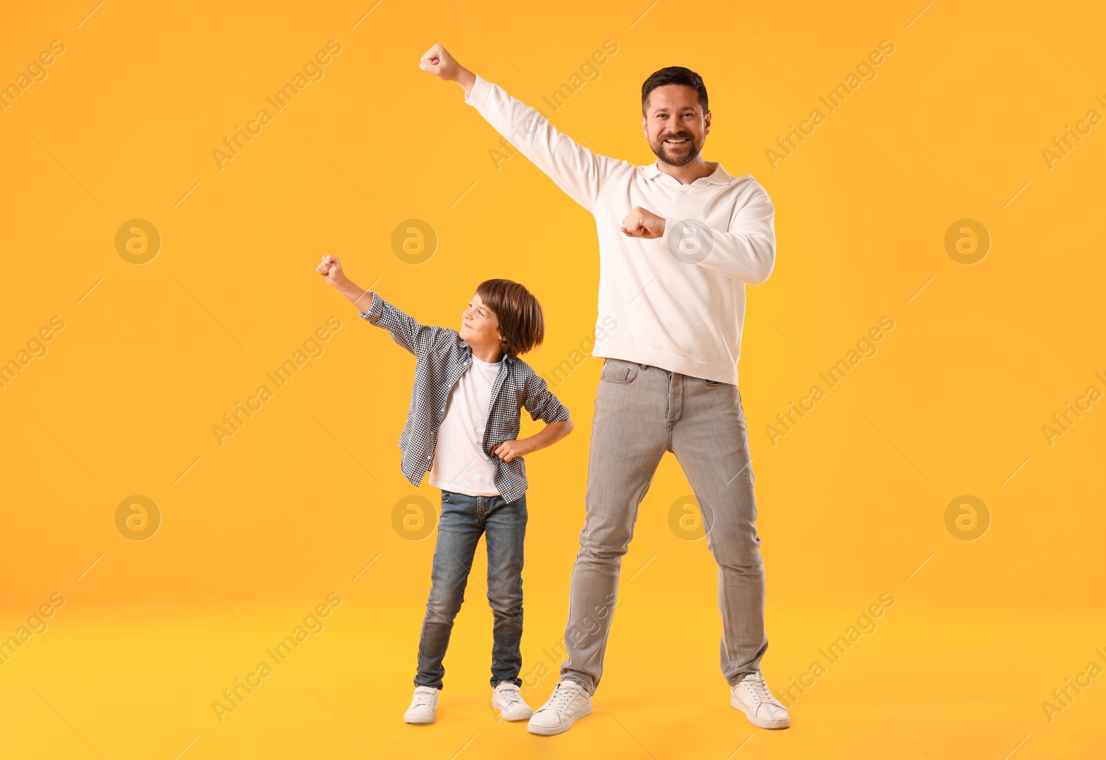 Father and son having fun on yellow background Photo of Father and son having fun on yellow background