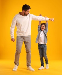 Photo of Father and son having fun on yellow background