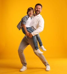 Photo of Father and son having fun on yellow background