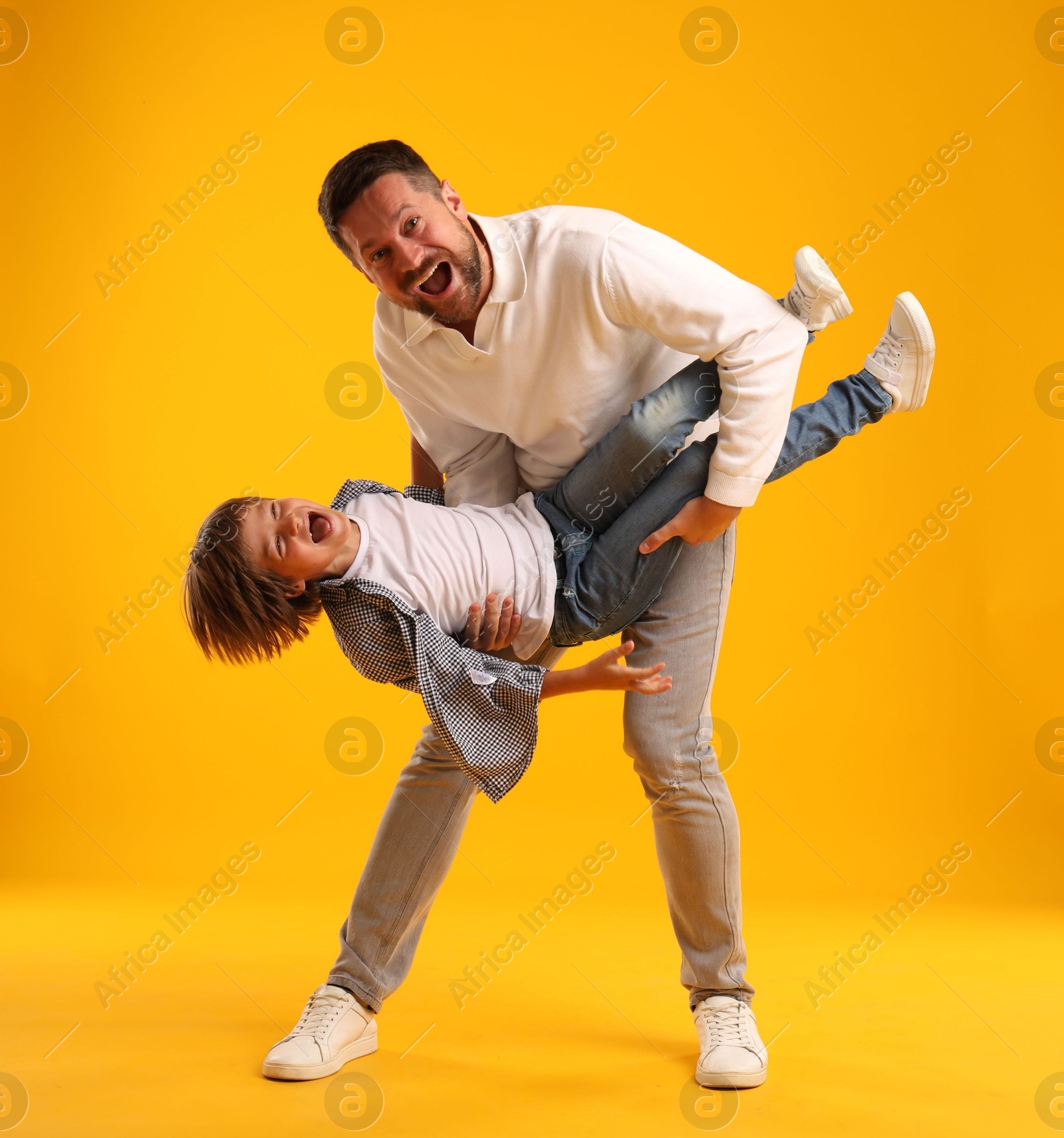 Father and son having fun on yellow background Photo of Father and son having fun on yellow background