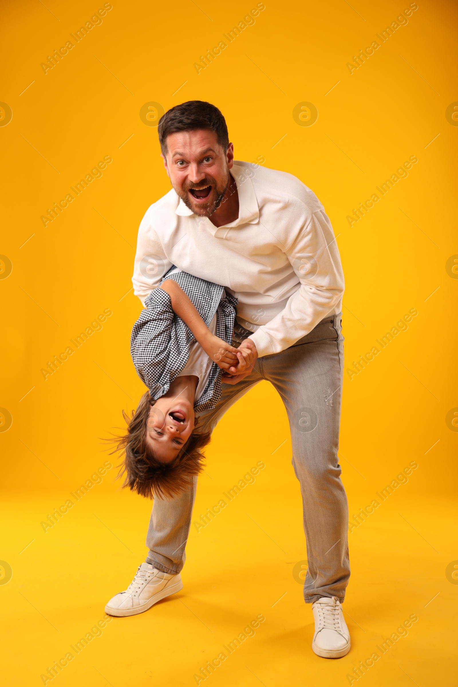 Father and son having fun on yellow background Photo of Father and son having fun on yellow background