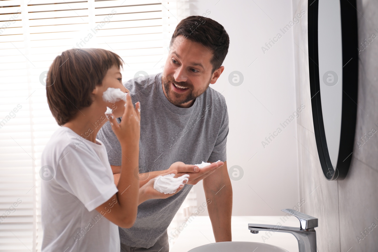 Photo of Father and son applying shaving foam on their faces in bathroom