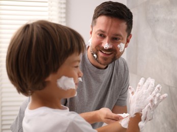 Photo of Father and son applying shaving foam on their faces in bathroom
