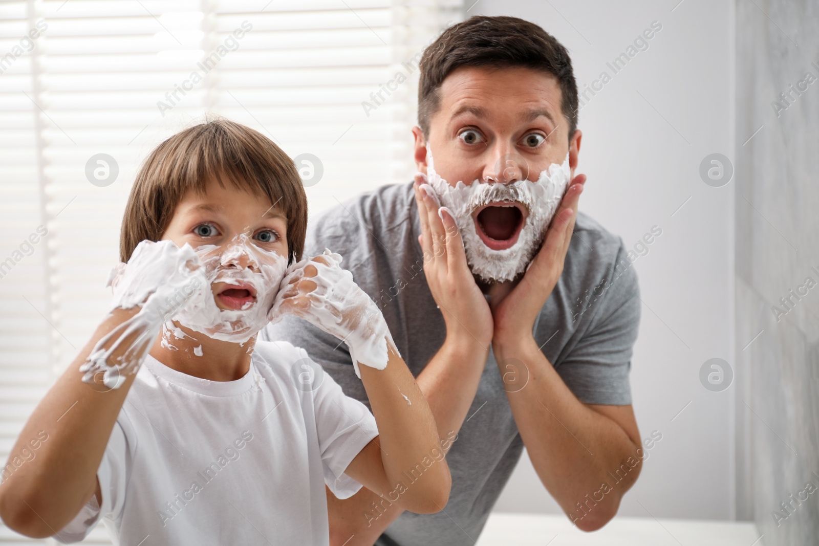 Father and son with shaving foam on their faces in bathroom Photo of Father and son with shaving foam on their faces in bathroom