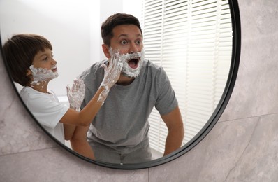 Photo of Father and son with shaving foam on their faces in bathroom