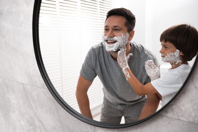 Photo of Father and son with shaving foam on their faces in bathroom