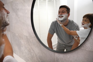 Photo of Father and son with shaving foam on their faces in bathroom